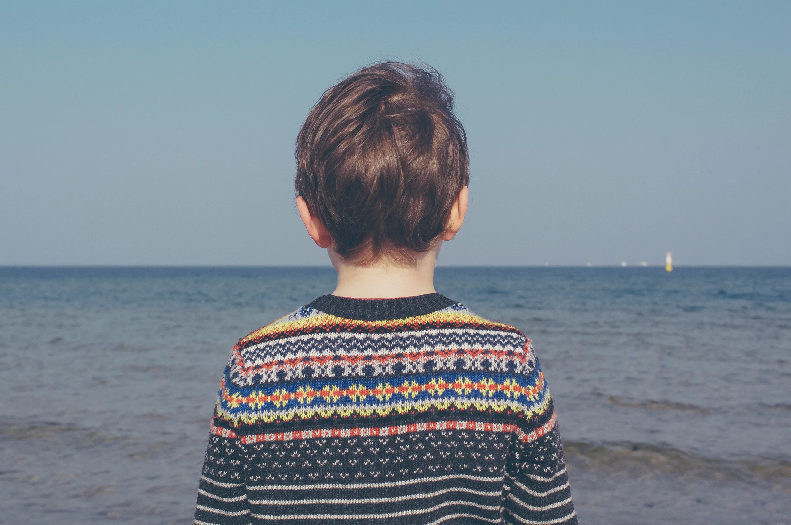 Back of Boy Standing Facing Ocean